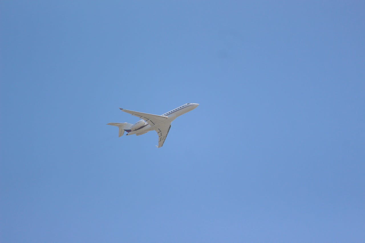 A private jet soars through a clear blue sky, symbolizing luxury air travel.